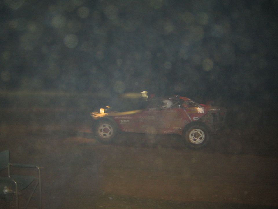Dark red off-road race buggy number 700 driving at night