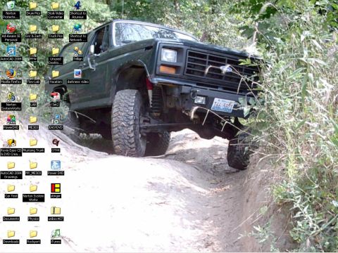 1986 Ford Bronco - This lifted 4x4 is navigating a challenging off-road path through dense vegetation.