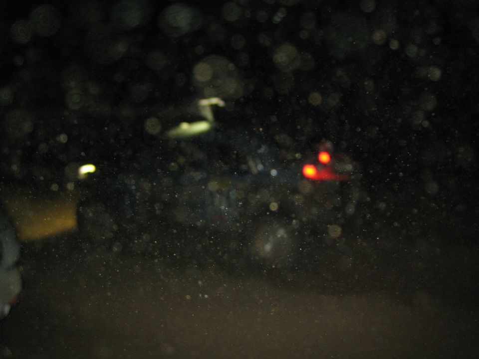 Dark blurry nighttime photo of a vehicle with red tail lights