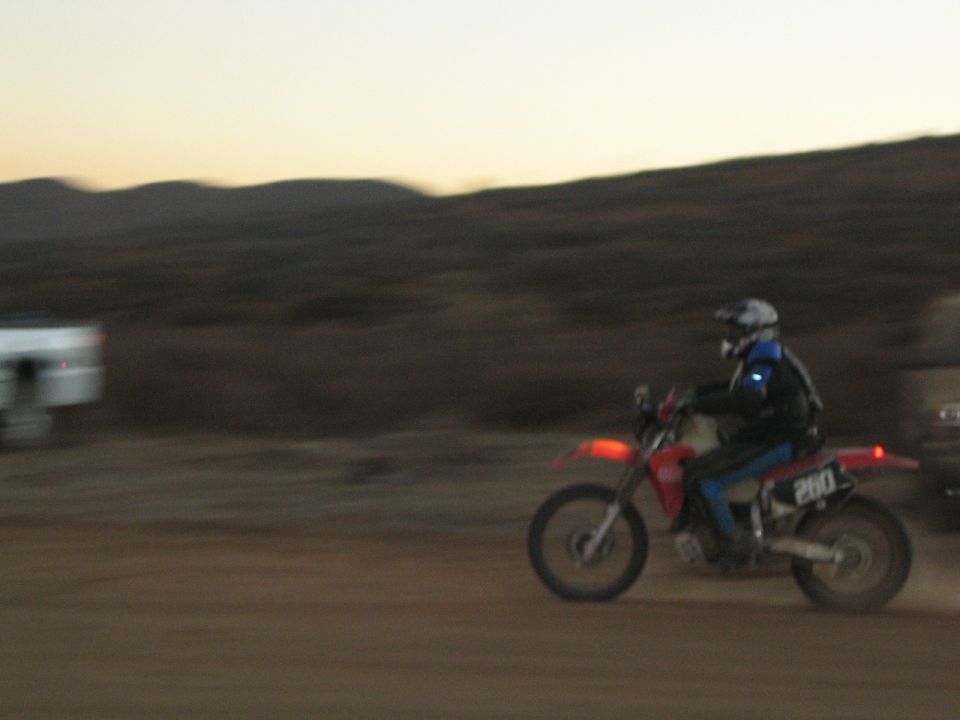 Rider on red and blue dirt bike number 260 riding at dusk