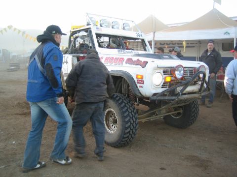 Crew pushing white Bronco race truck 304 in a foggy pit
