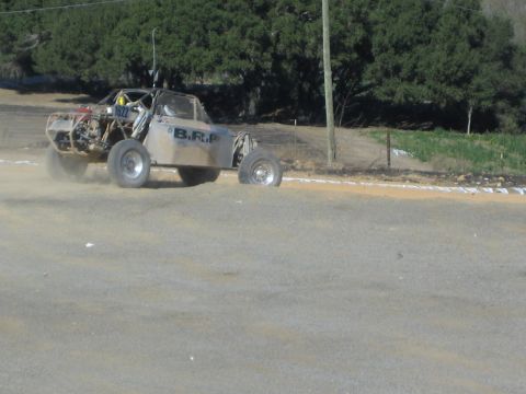 Single-seat off-road race buggy on a dirt track lettered B.R.P