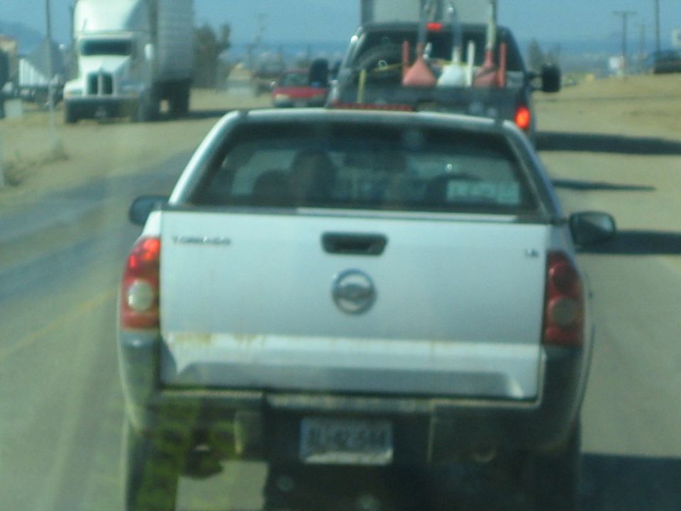 Rear of a silver Chevrolet Tornado pickup following traffic on a highway