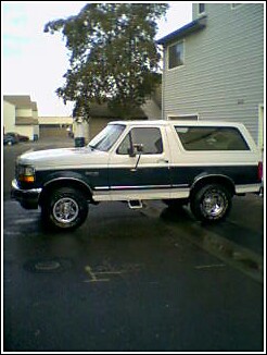 1995 Ford Bronco - Two-tone 1995 Ford Bronco parked outside a building. Supermotors.net logo visible.