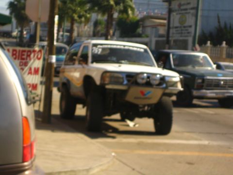 Lifted off-road race SUV with light bar numbered 767 on a street