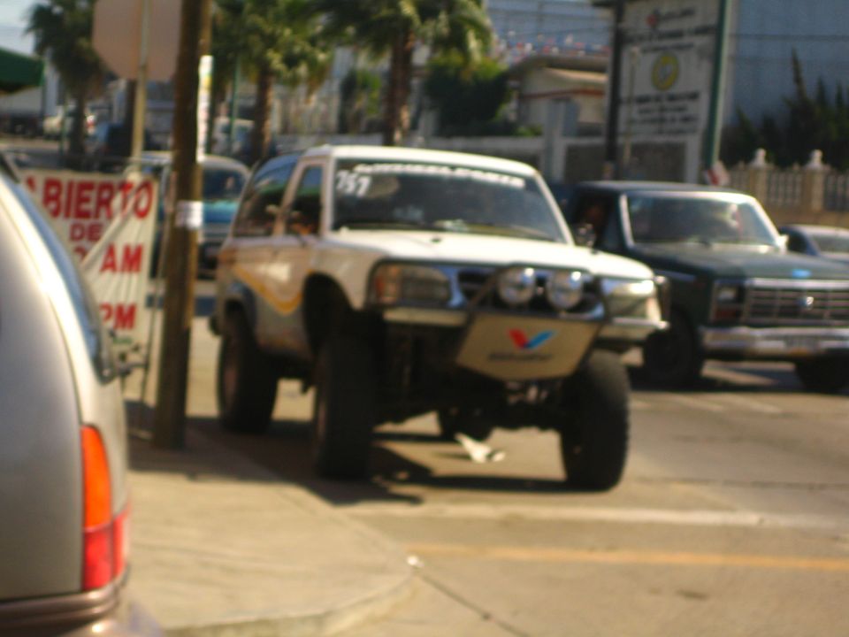 Lifted off-road race SUV with light bar numbered 767 on a street