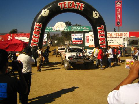 Off-road race truck staged under an inflatable Tecate start arch