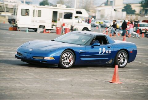 1997 Ford Probe - A blue Chevrolet Corvette C5 navigates a course, displaying racing numbers on its door.