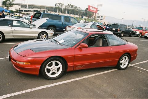 1997 Ford Probe - A red Ford Probe GT with a black hood is parked in a lot next to other vehicles.