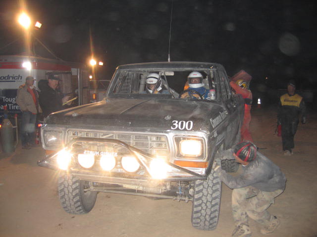 Black race pickup numbered 300 with helmeted crew at night