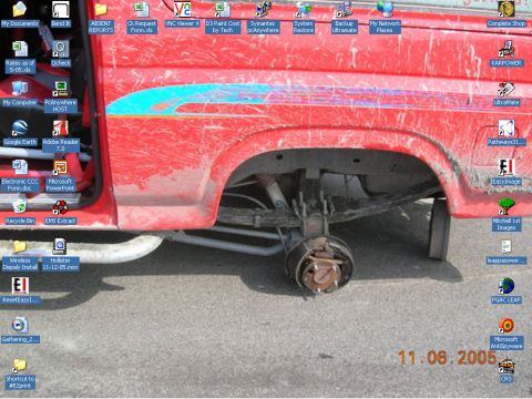 1985 Ford Bronco - This photo shows the rear axle and suspension of a red pickup truck, missing its wheel.