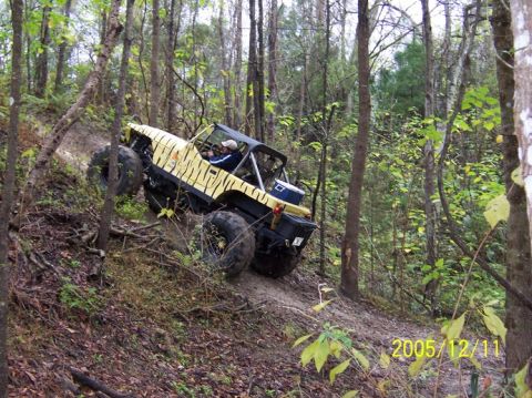 1989 Ford Bronco - A modified off-road vehicle navigates a steep, wooded trail.
