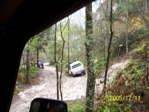 1989 Ford Bronco - Off-roading in the woods on a cloudy day, with two vehicles navigating a dirt path.