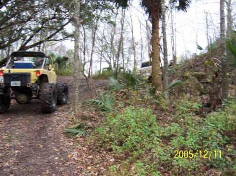 1989 Ford Bronco - Off-road vehicles navigate a wooded trail with rocky terrain.