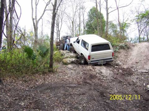 1989 Ford Bronco - A white 1989 Ford Bronco navigates a challenging off-road course with another vehicle visible in the background.