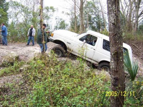 1989 Ford Bronco - 1989 Ford Bronco tackling an off-road trail with onlookers present.