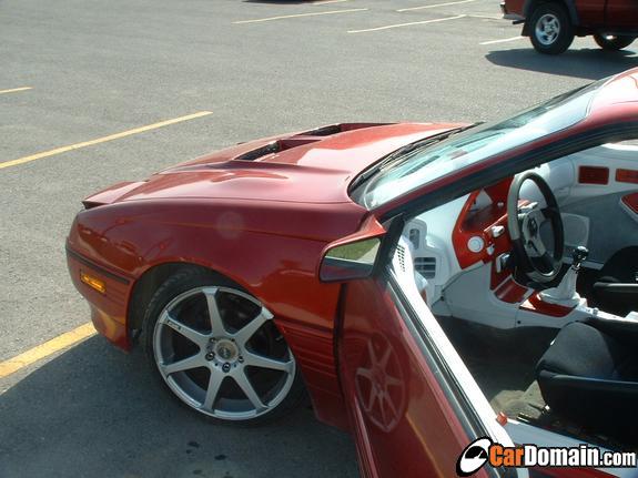 Red coupe with door open showing white/red custom interior and silver alloy wheels