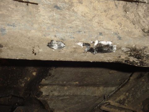 1989 Ford Bronco - Close-up view of the underside of a vehicle, showing a metal beam with paint markings.