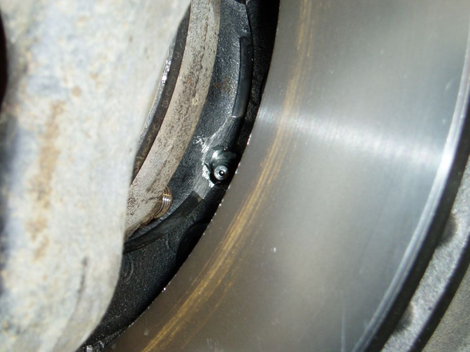 Close-up of a brake caliper grease fitting near a rotor