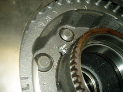 2000 Ford E350 - A close-up view of a rusty wheel hub assembly, showing a small bolt and gear teeth.