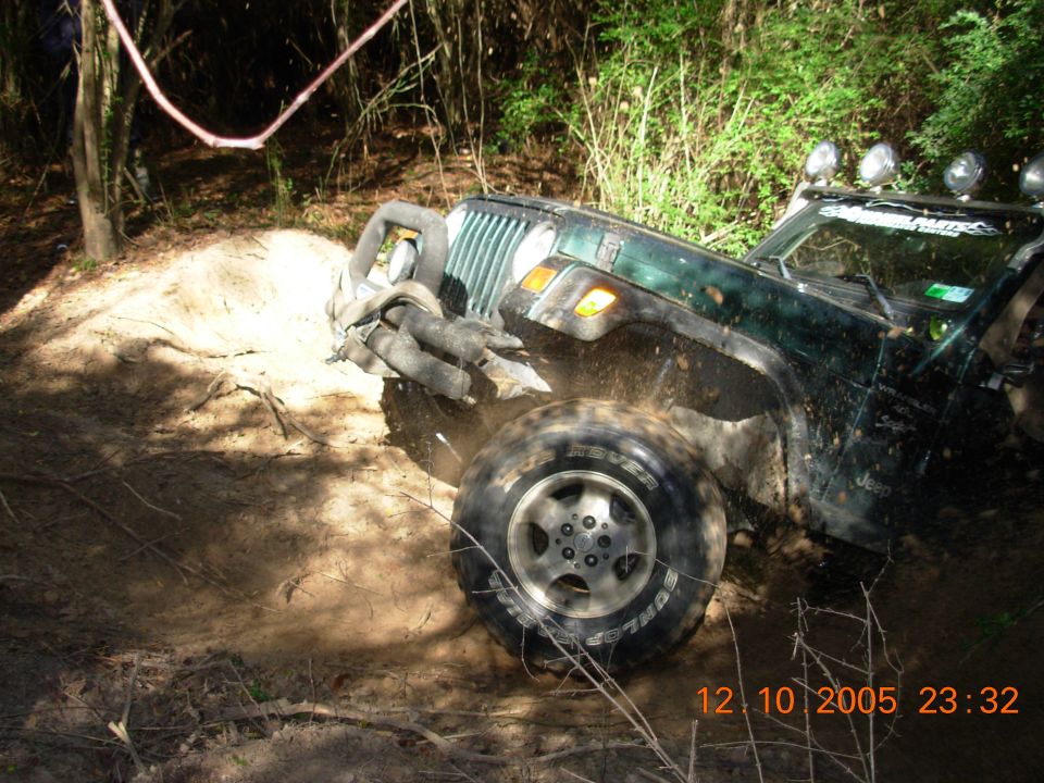 Green Jeep Wrangler stuck in mud, front 3/4 view