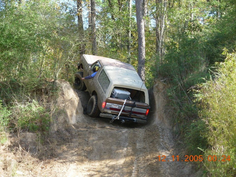 Brown and white Ford Bronco on a dirt trail, rear view. Cooler in the cargo area