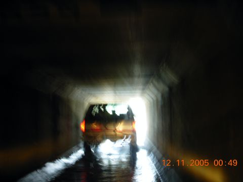 1987 Ford Bronco - A dark SUV is seen from behind as it drives through a tunnel with water on the road.