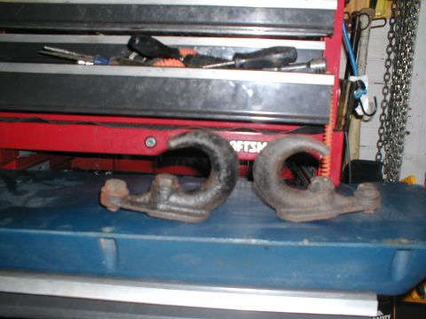 1979 Ford Bronco - Two rusty tow hooks are displayed in front of a toolbox, with tools visible inside.