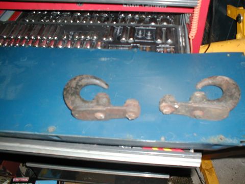 1979 Ford Bronco - Two tow hooks are shown on a blue surface, with a toolbox filled with tools visible behind them.