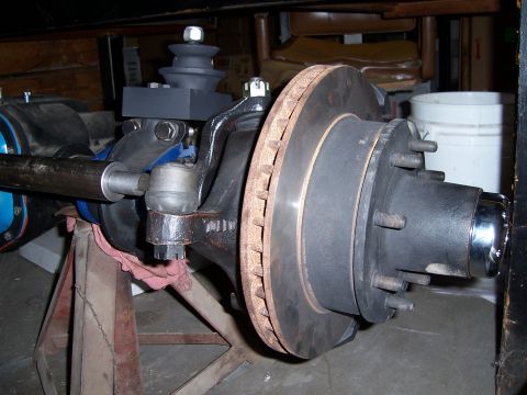 1983 Ford Bronco - This image shows a close-up view of a vehicle's front axle, brake rotor, and hub assembly, which is currently supported by jack stands.