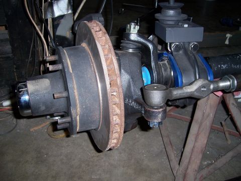 1983 Ford Bronco - Close-up view of a vehicle's front axle steering and brake assembly, a disc brake rotor and tie rod end.