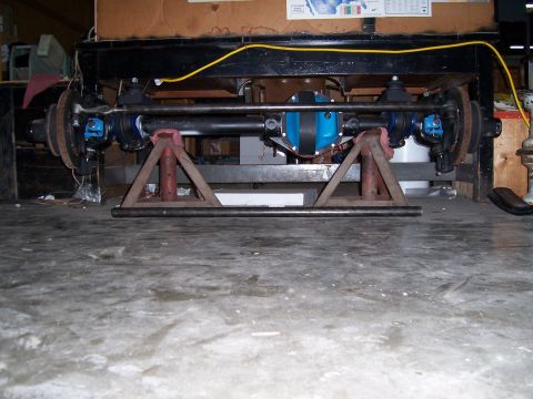 1983 Ford Bronco - A front axle assembly, a blue differential housing, is supported by triangular stands in a workshop setting.