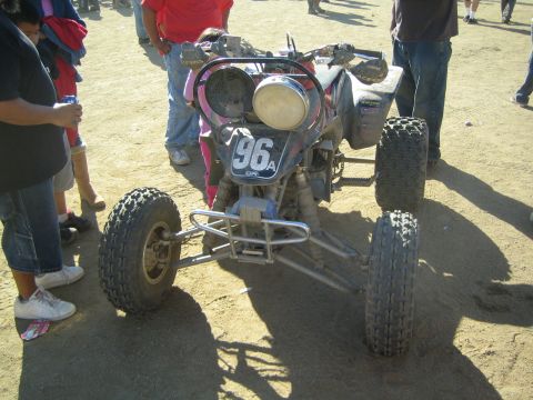Off-road race quad ATV numbered 96 parked on dirt with spectators