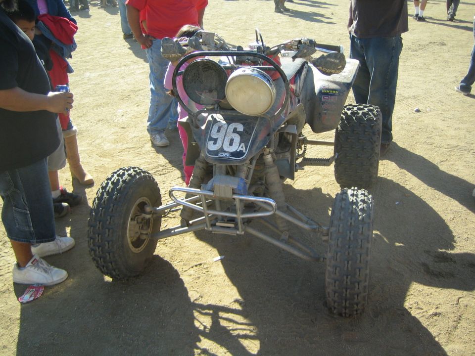 Off-road race quad ATV numbered 96 parked on dirt with spectators