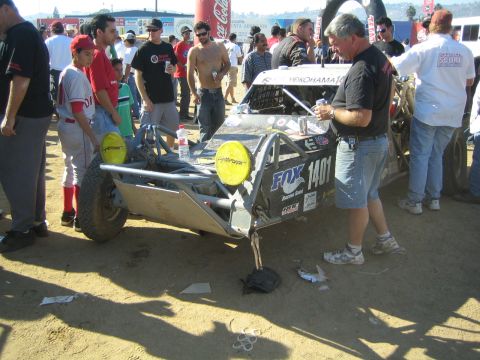 Single-seat race buggy numbered 1401 in a pit crowd with crew working