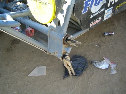 Close-up of a race buggy front suspension and broken steering arm on dirt