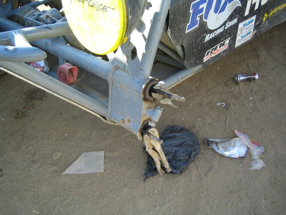 Close-up of a race buggy front suspension and broken steering arm on dirt