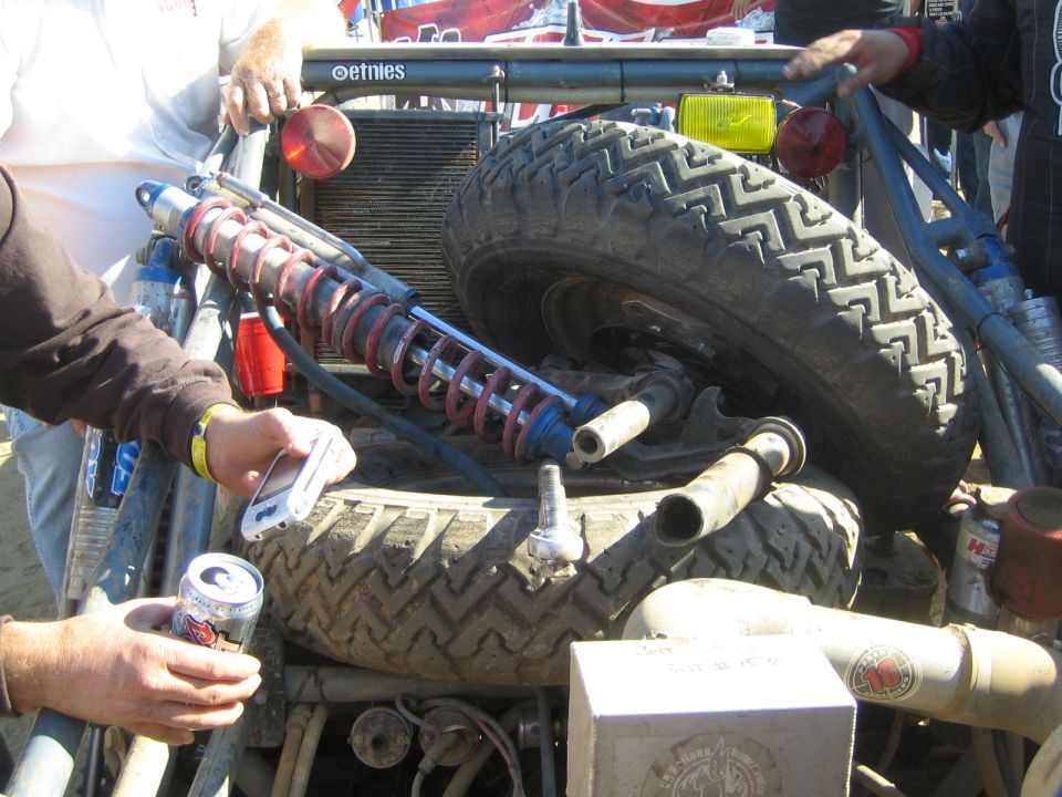 Close-up of an off-road vehicle's rear shock, coilover spring, and spare tires