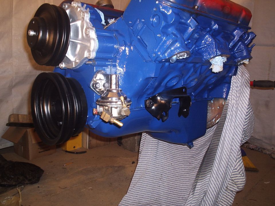 Close-up of a blue engine block with a chrome fuel pump and black pulleys attached