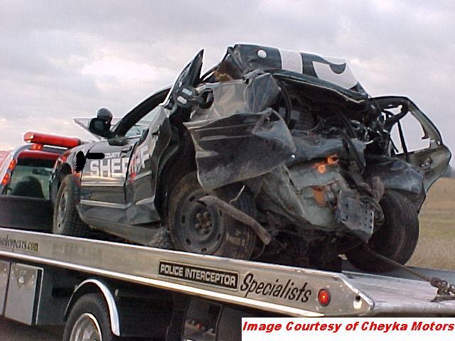 Heavily damaged black sheriff's car on a tow truck