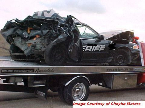 2000 Ford Crown Victoria - A heavily damaged sheriff's vehicle is transported on a flatbed tow truck.