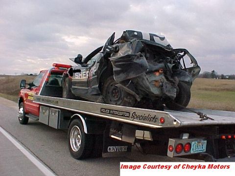 2000 Ford Crown Victoria - A severely damaged police car, marked 'SHERIFF', is transported on the back of a tow truck.