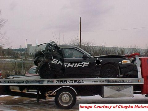 2000 Ford Crown Victoria - A heavily damaged sheriff's car is being transported on a flatbed tow truck.