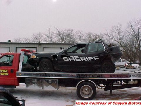 2000 Ford Crown Victoria - A wrecked county sheriff's car is loaded onto a tow truck for transport.