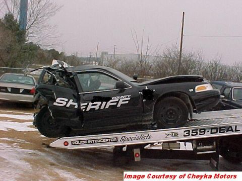 2000 Ford Crown Victoria - A heavily damaged black 2000 Ford Crown Victoria Police Interceptor is loaded onto a tow truck.