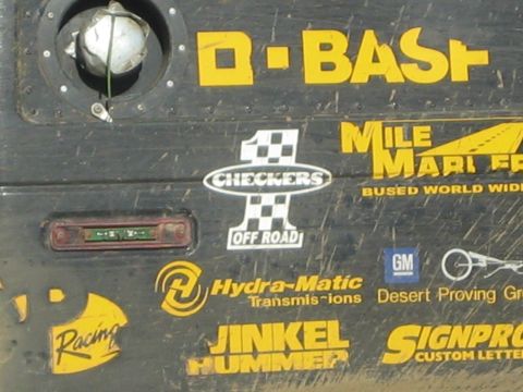 Close-up of a black race vehicle panel with BASF, Checkers Off Road, Hydra-Matic, and GM decals