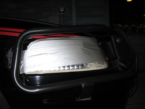 2000 Ford Crown Victoria - A car mirror is crudely repaired with silver duct tape, obscuring its original condition.