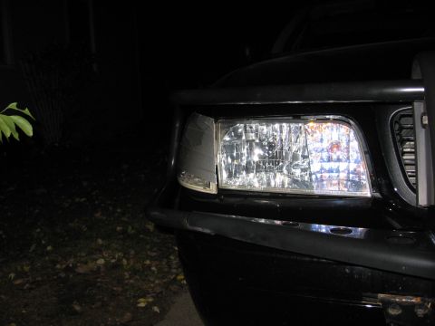 2000 Ford Crown Victoria - Close-up of the front headlight and grille assembly on a black 2000 Ford Crown Victoria with a bull bar.