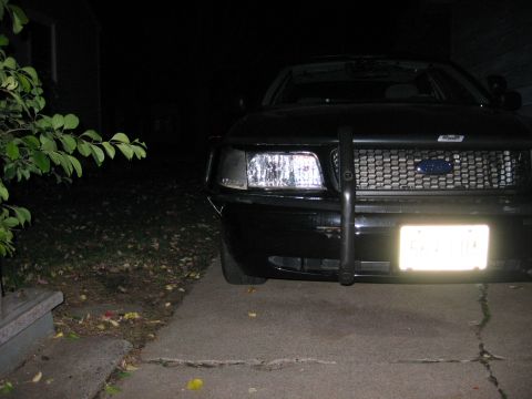 2000 Ford Crown Victoria - A black 2000 Ford Crown Victoria with a push bar is parked in front of a house at night.