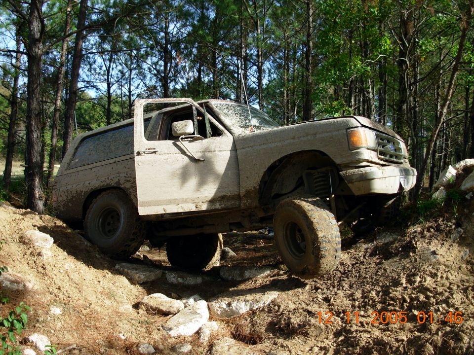 1987 Ford Bronco off-roading, front 3/4 view, covered in mud